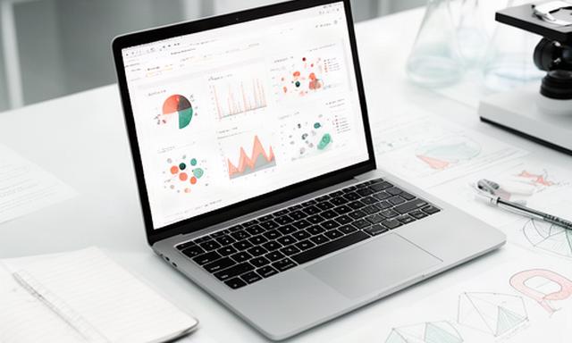 Interaktive Forschungsdaten auf einem Laptop neben Notizen und Diagrammen in einem Laborbüro